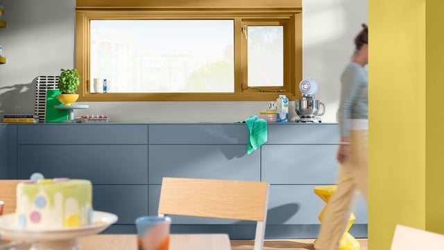 Hele köök siniste kappidega, valamu ja nõudega; inimene jalutab mööda.